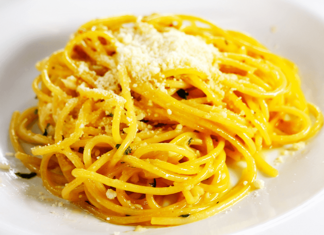 Creamy spaghetti with cheese topping on a white plate.